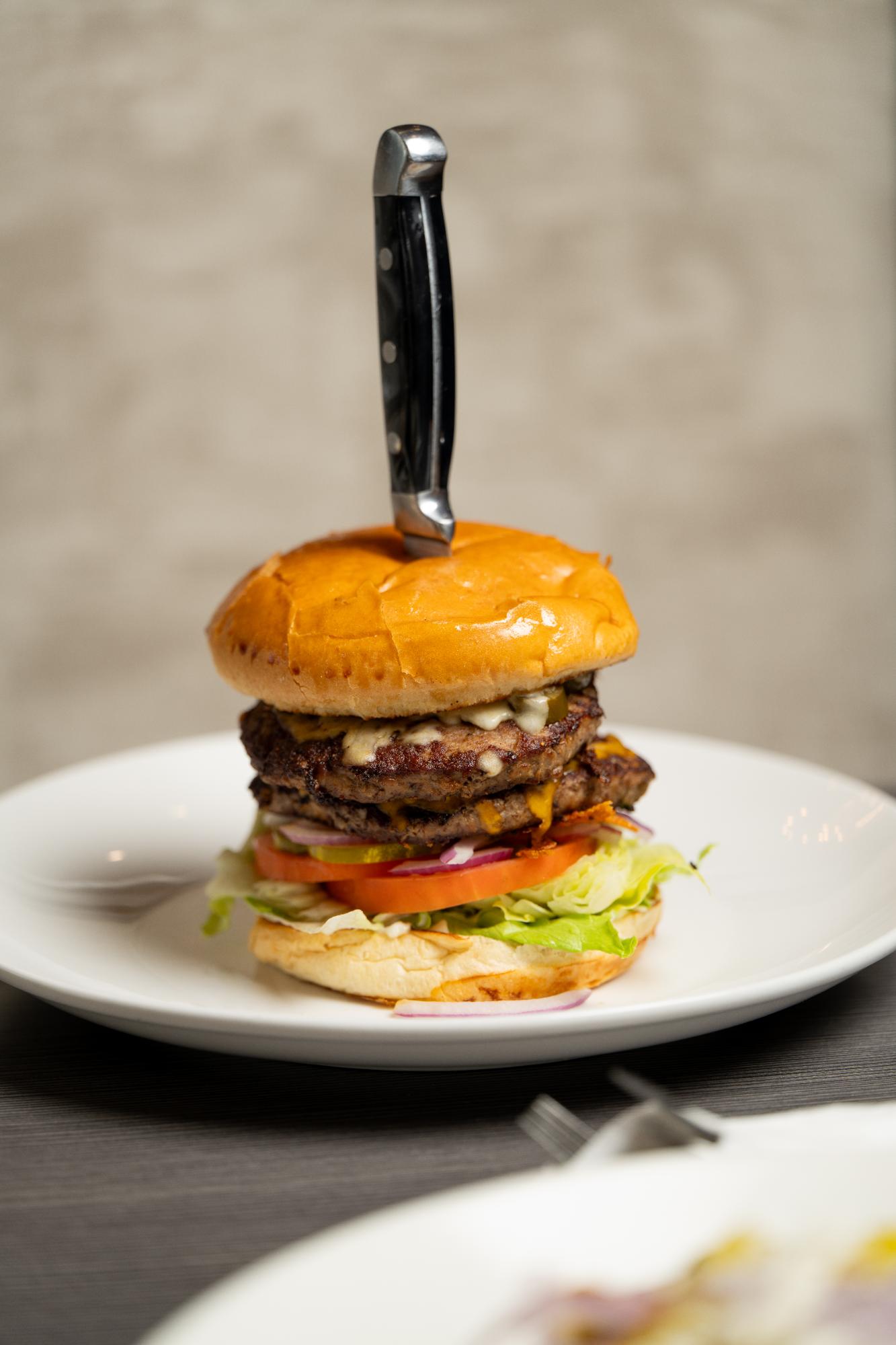 Joe's Burger stacked high with a steak knife through the bun
